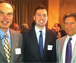 Three Men in Suits, Smiling and Standing Together at an Event