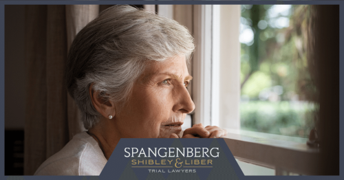 Elderly Woman Staring Out Of A Window In A Nursing Home