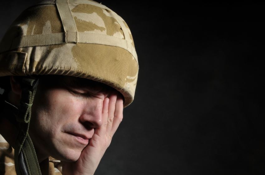 Soldier holding one hand over eye