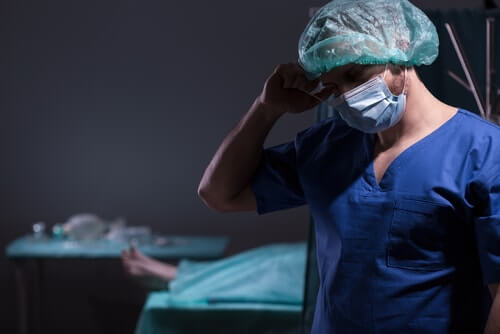 Surgeon Holding His Head in Dark Room