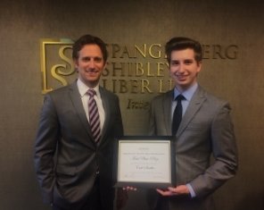 Two Men in Suits Standing and Smiling Together, One of Them a Scholarship Winner Showing Off His Prize