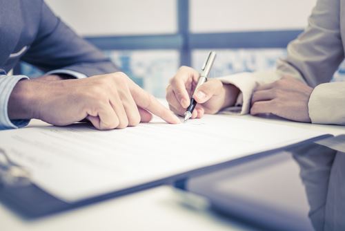 Man Pointing on Clipboard Where to Sign While Another Man Signs