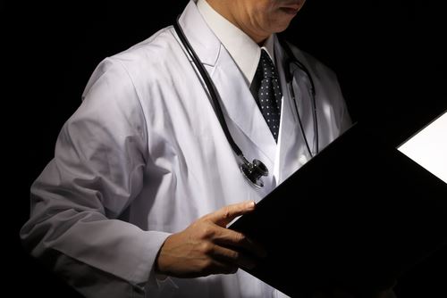 Doctor With a Stethoscope Around His Neck Reading Notes
