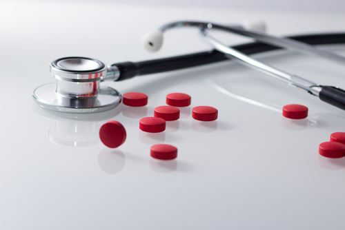 Stethescope Beside Loose Pills on a Glass Table